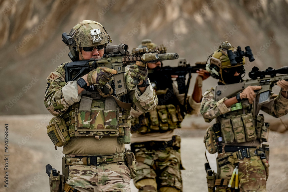 Fototapeta premium A group of military men in combat gear patrol in the middle of a desert and tropical jungle. Soldiers in full combat gear in dry weather conditions assemble and march on a mission.