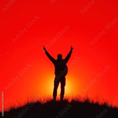 Silhouette of a hiker with arms raised against a fiery sunset