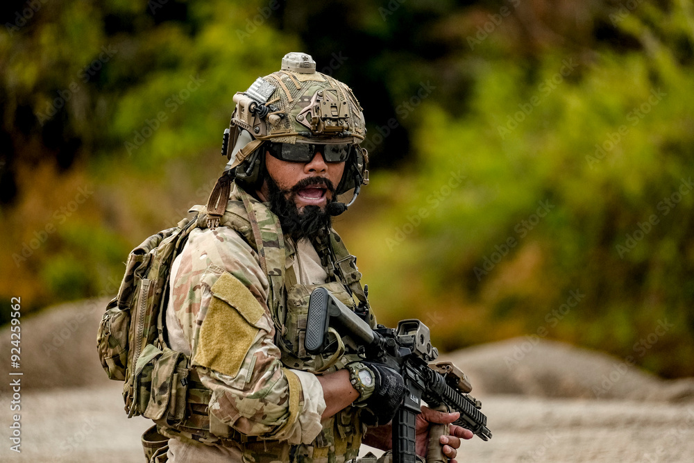 A group of military men in combat gear patrol in the middle of a desert and tropical jungle. Soldiers in full combat gear in dry weather conditions assemble and march on a mission.