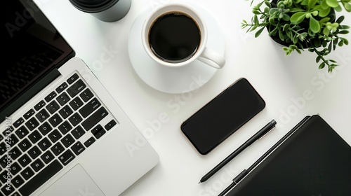 Flatlay of White Desk with Black Laptop, Smartphone, Coffee Cup, and Pen.