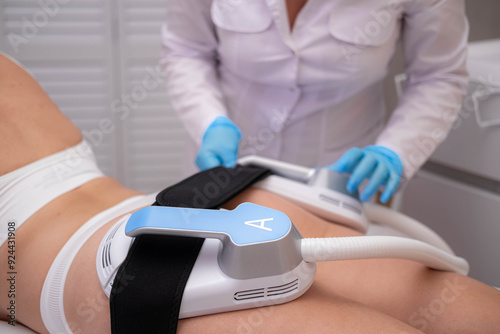 professional electrostimulation session, close up view o therapist applying EMS device on woman in modern clinic, muscle toning, body sculpting, fitness industry