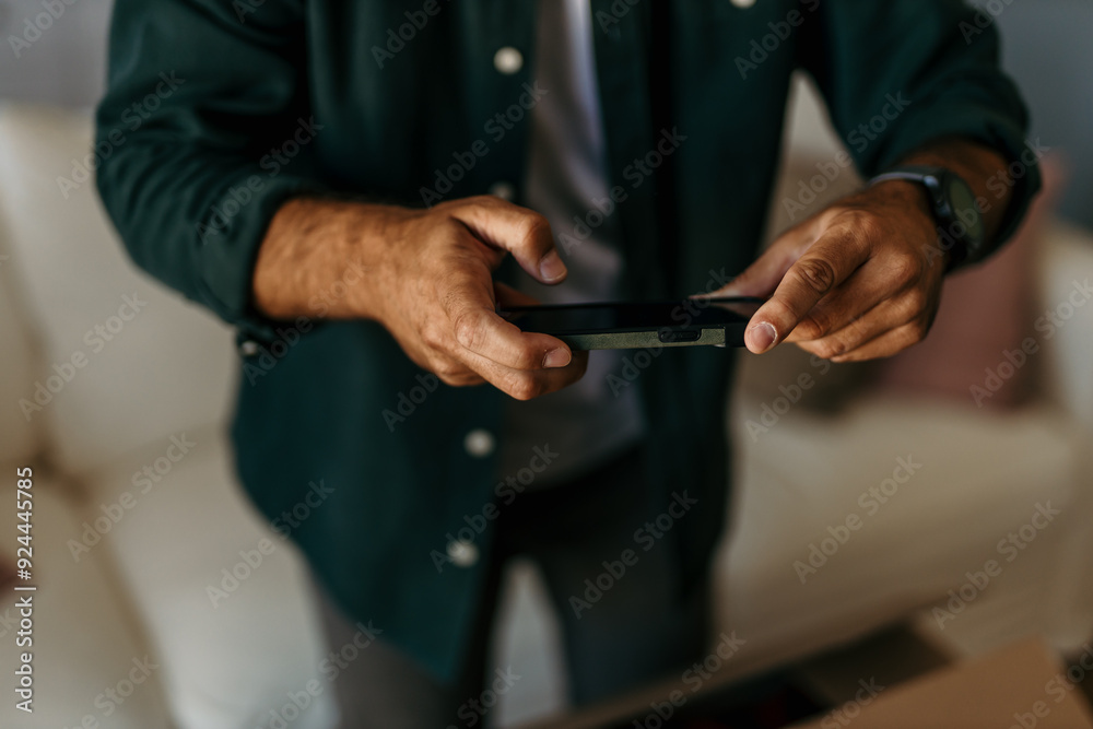 An unrecognizable man taking a photo with a smartphone of a packed box during a moving house An unrecognizable man taking a photo with a smartphone of a packed box during a moving house
