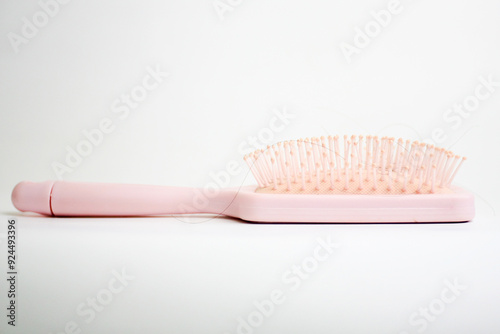 Hairbrush with strands of black hair stuck in it isolated on white background photo