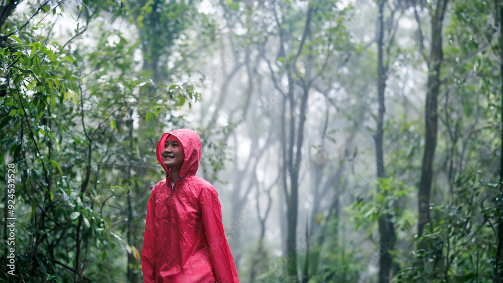 Smiling woman hiking through lush, misty forest on a rainy day Smiling woman hiking through lush, misty forest on a rainy day
