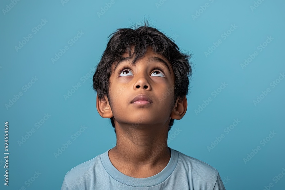 A young boy with dark hair and brown eyes is looking up at the sky A young boy with dark hair and brown eyes is looking up at the sky