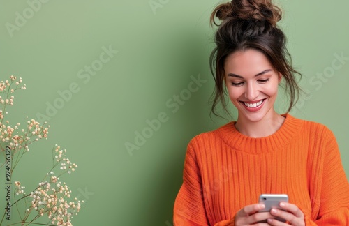 Young Woman Smiling While Texting on Smartphone Against Green Background