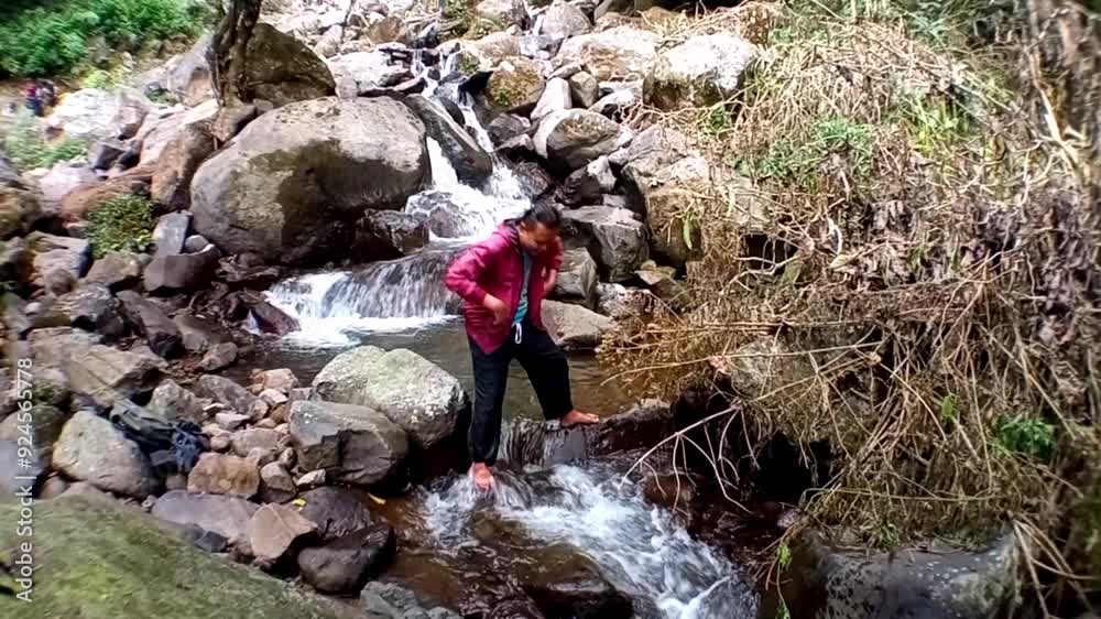 A man enjoys the natural atmosphere, feeling the freshness of the mountain air and the coldness of the river water. A man enjoys the natural atmosphere, feeling the freshness of the mountain air and the coldness of the river water.