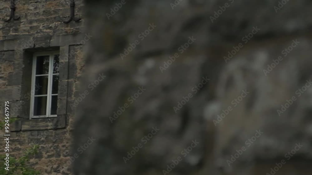 Sliding shot of an old medieval stone building with white wooden windows Sliding shot of an old medieval stone building with white wooden windows
