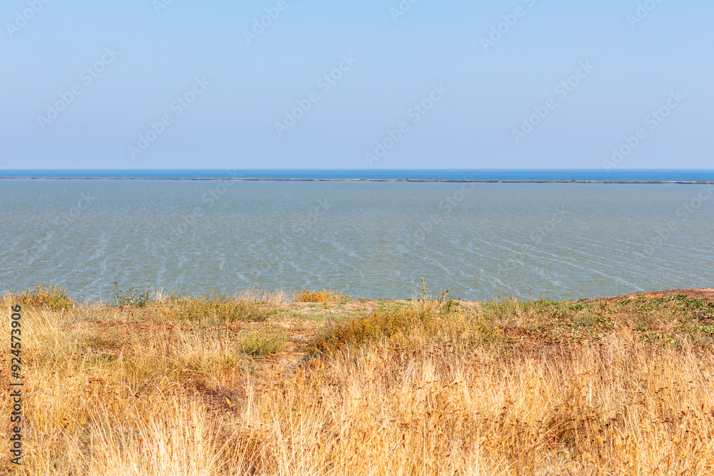 Waters below surrounded by lush greenery and a clear sky. Grass is dry on the coast in the summer Waters below surrounded by lush greenery and a clear sky. Grass is dry on the coast in the summer