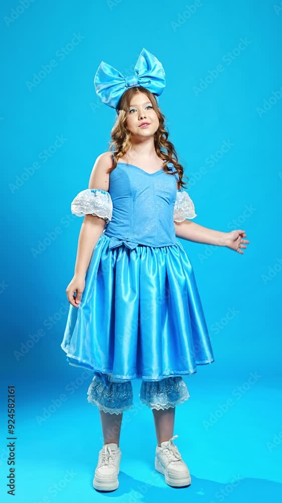 Cute teenage girl in blue doll costume singing, gestures on blue background. Cute teenage girl in blue doll costume singing, gestures on blue background.