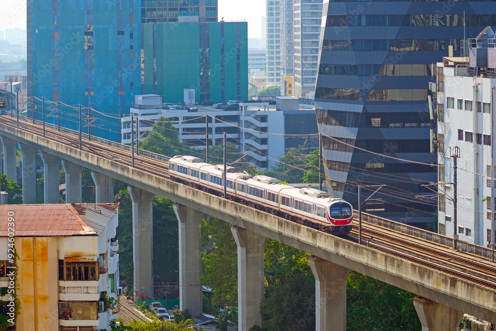 Modern train metro viaduct moving on rails above the ground in the city skyscrapers. Subway cars traveling across the bridge, public rapid transit. Modern train metro viaduct moving on rails above the ground in the city skyscrapers. Subway cars traveling across the bridge, public rapid transit.
