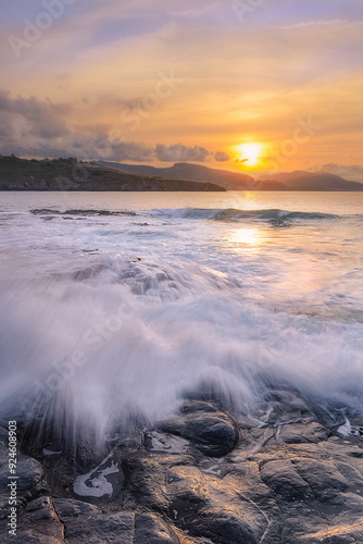 Sunset over the Cantabrian Sea at Lastron beach, Zierbana, Bizkaia with the waves between the rocks on the shore photo