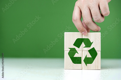 Hand places wooden blocks with green recycling icons. Concepts of Environmental , ecology, CSR, zero waste, Net Zero, and World Environment Day. with copy space