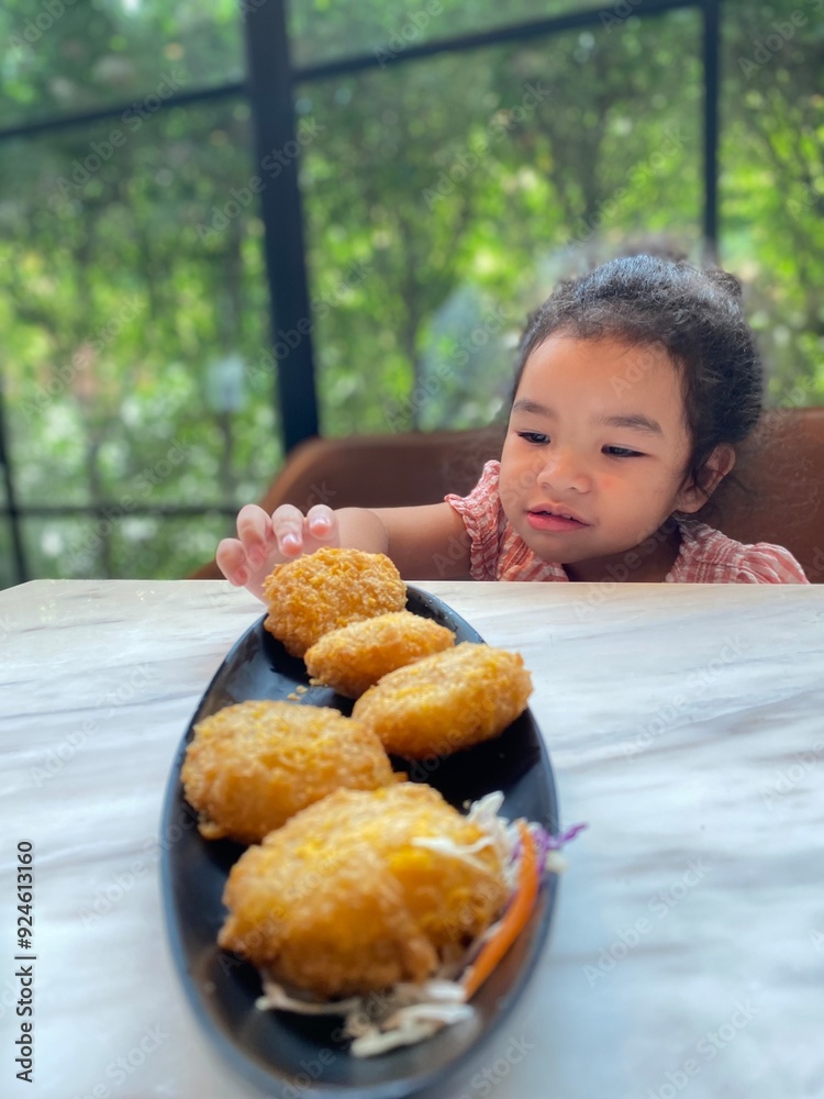 Cute Asian little girl eating deep fried shrimp nuggets in cafe Cute Asian little girl eating deep fried shrimp nuggets in cafe