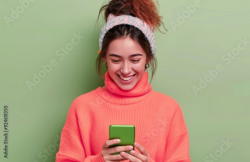 Young Woman Smiling While Texting on Smartphone Against Green Background