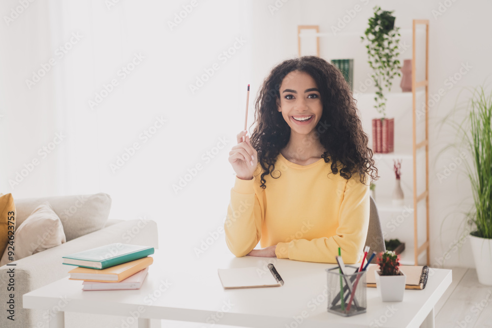 Photo of teenager young wavy hair american clever girl in yellow shirt sitting workplace doing homework for college indoors Photo of teenager young wavy hair american clever girl in yellow shirt sitting workplace doing homework for college indoors
