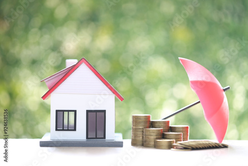 Protection, Stack of coins money and Model house with hand holding the umbrella on natural green background, Finance insurance and Safe investment concept photo