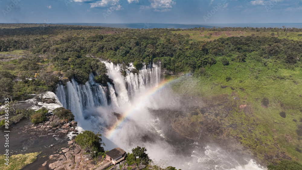 Fototapeta premium Kalandula Waterfall cascading beautifully in Angola with a rainbow forming in the mist under a clear blue sky