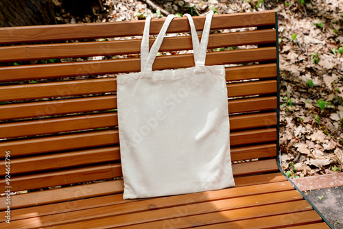 White tote cotton bag on wooden bench in the park mockup. Canvas isolated shopper, eco friendly concept. Zero waste, reusable, healthy lifestyle. Place for text, logo, design photo