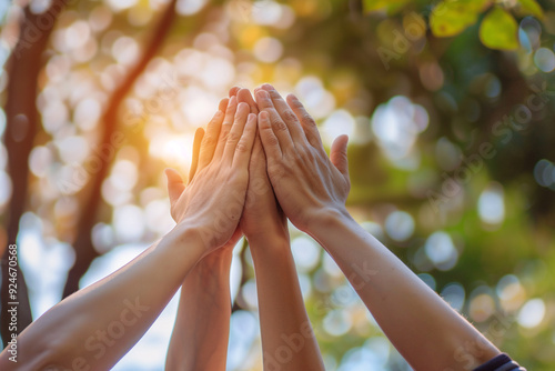 Teamwork. Team harmony. Team building. People high five each other in front of trees. Only hands are visible. photo