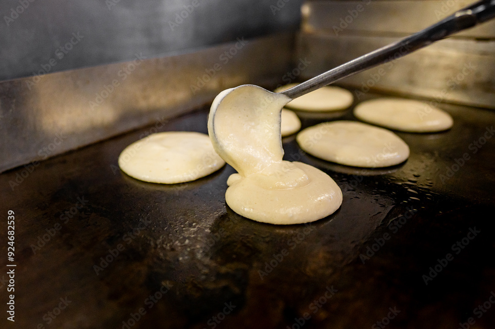 Close-up of pancake batter being poured onto a hot griddle, capturing motion and texture. image highlights the cooking process with a focus on smooth, creamy batter and the sizzling griddle surface. Close-up of pancake batter being poured onto a hot griddle, capturing motion and texture. image highlights the cooking process with a focus on smooth, creamy batter and the sizzling griddle surface.