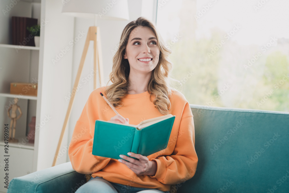 Photo of attractive young woman sit couch write notebook look empty space dressed orange outfit cozy day light home interior living room Photo of attractive young woman sit couch write notebook look empty space dressed orange outfit cozy day light home interior living room