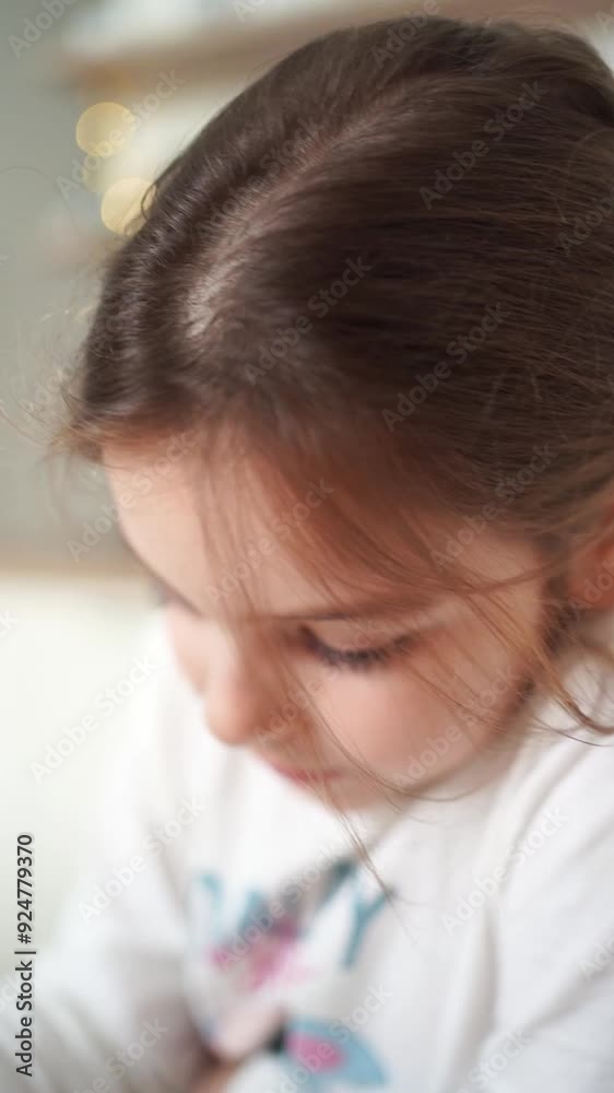 Close-up of a young girl intently drawing on paper at a wooden table in a cozy indoor setting Close-up of a young girl intently drawing on paper at a wooden table in a cozy indoor setting