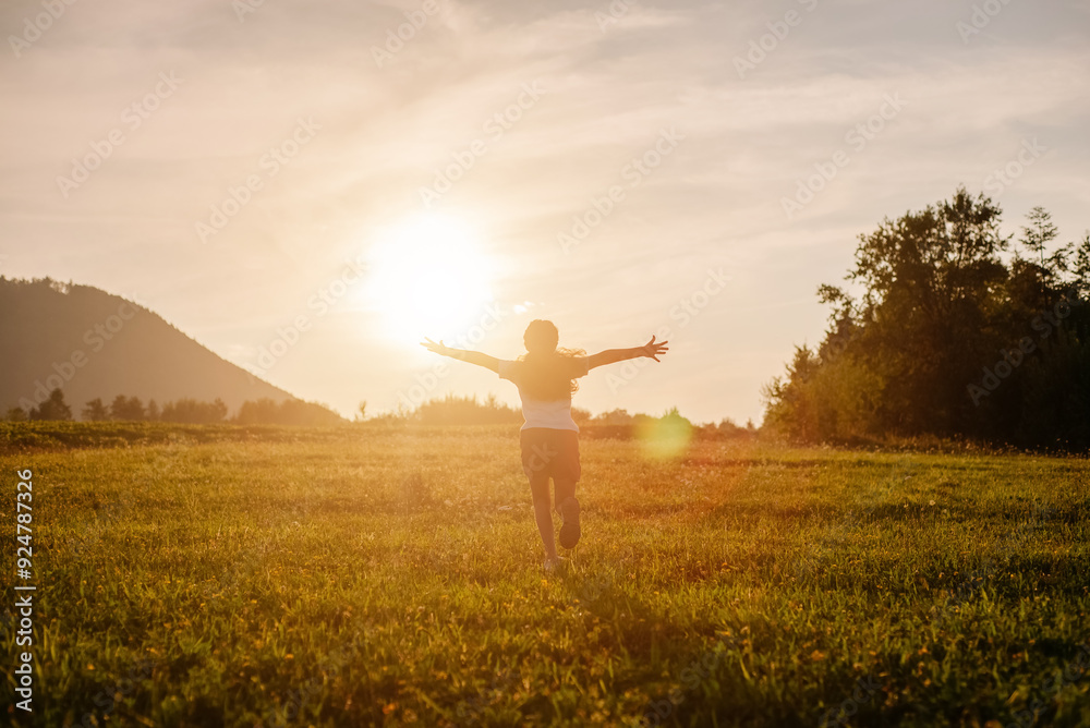 Happy little girl running on background mountains and sky during amazing summer sunset. Child runs with arms raised like wings of an airplane, childhood dream holiday. Kid dream, airplane pilot Happy little girl running on background mountains and sky during amazing summer sunset. Child runs with arms raised like wings of an airplane, childhood dream holiday. Kid dream, airplane pilot