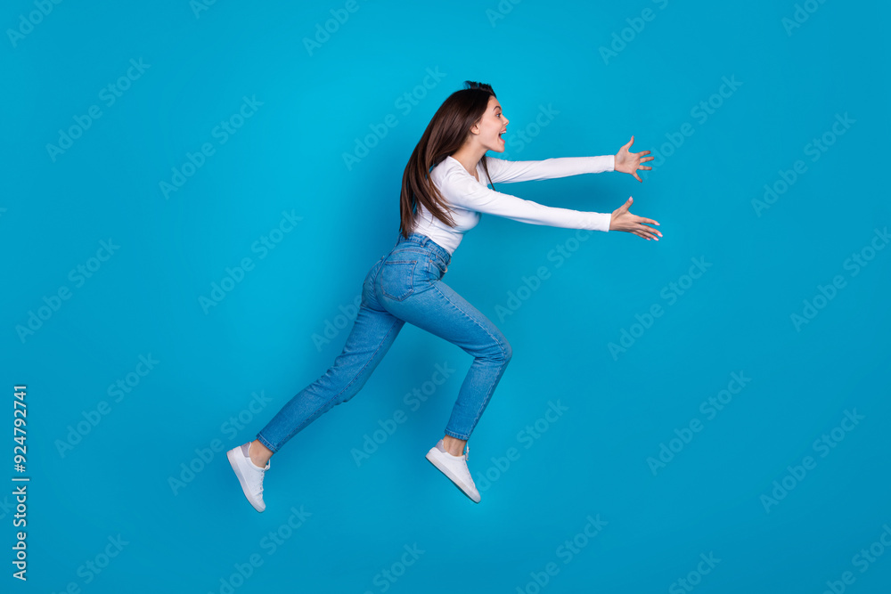 Full body photo of attractive teen woman running fast catching empty space dressed stylish white clothes isolated on blue color background