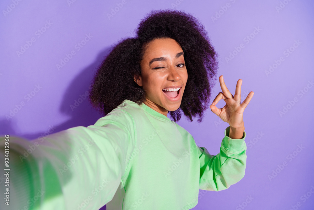 Self portrait of american young funky woman blink eye showing okey symbol photographing herself isolated on purple color background Self portrait of american young funky woman blink eye showing okey symbol photographing herself isolated on purple color background