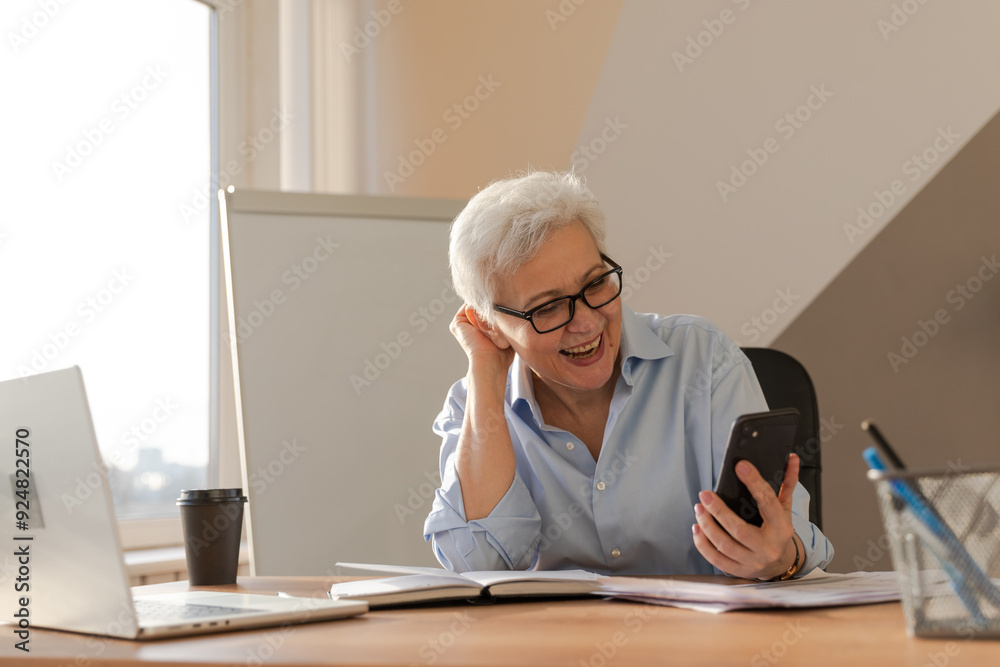 Confident middle aged senior woman euphoric winner with smartphone. Older mature lady looking at cell phone reading great news getting good result winning online bid feeling amazed. Winning gesture Confident middle aged senior woman euphoric winner with smartphone. Older mature lady looking at cell phone reading great news getting good result winning online bid feeling amazed. Winning gesture