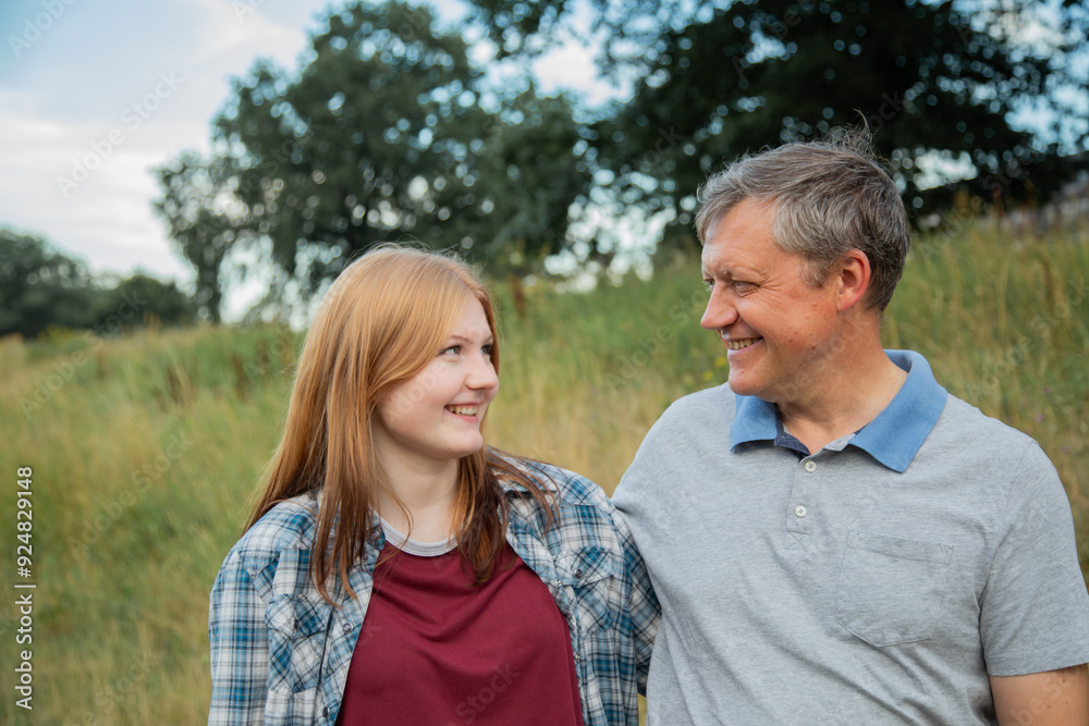 father and teenage daughter relaxing together outdoors in summer father and teenage daughter relaxing together outdoors in summer