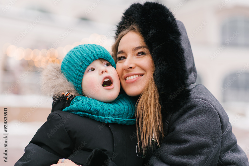 Happy mom and boy child are smiling at the camera in a snowy environment Happy mom and boy child are smiling at the camera in a snowy environment
