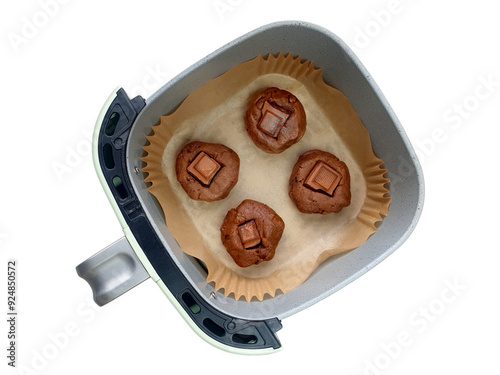 Baking homemade chocolate soft cookies or muffins with chocolate chunks in air fryer at the kitchen. Close up top view, isolated on white background with clipping path. Healthy cooking concept. photo