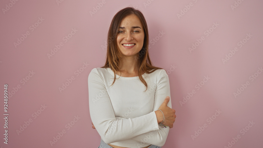 Attractive young caucasian woman with blonde hair smiling confidently while standing with arms crossed over an isolated pink wall background. Attractive young caucasian woman with blonde hair smiling confidently while standing with arms crossed over an isolated pink wall background.