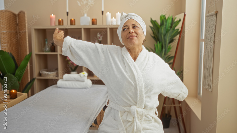 Obraz premium Woman stretching arms in a spa room with candles, plants, and wellness decor after a relaxing treatment