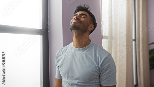 Photos Handsome young hispanic man enjoying a moment indoors at home in a bright living