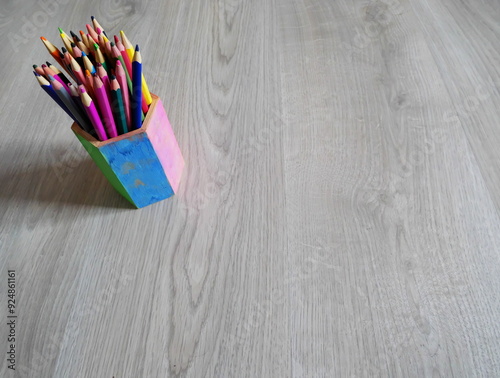 Colored pencils in an insulated pot on a wooden background photo