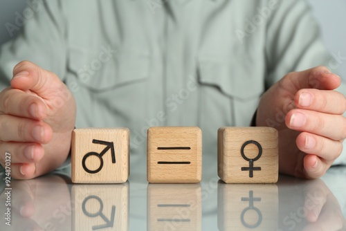 Gender equality concept. Woman with wooden cubes of male and female symbols at table, closeup