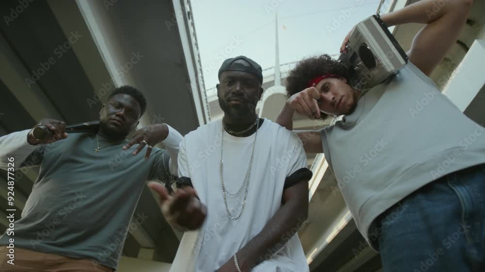 Low angle view of cool Black rapper looking at camera, showing hip hop ...