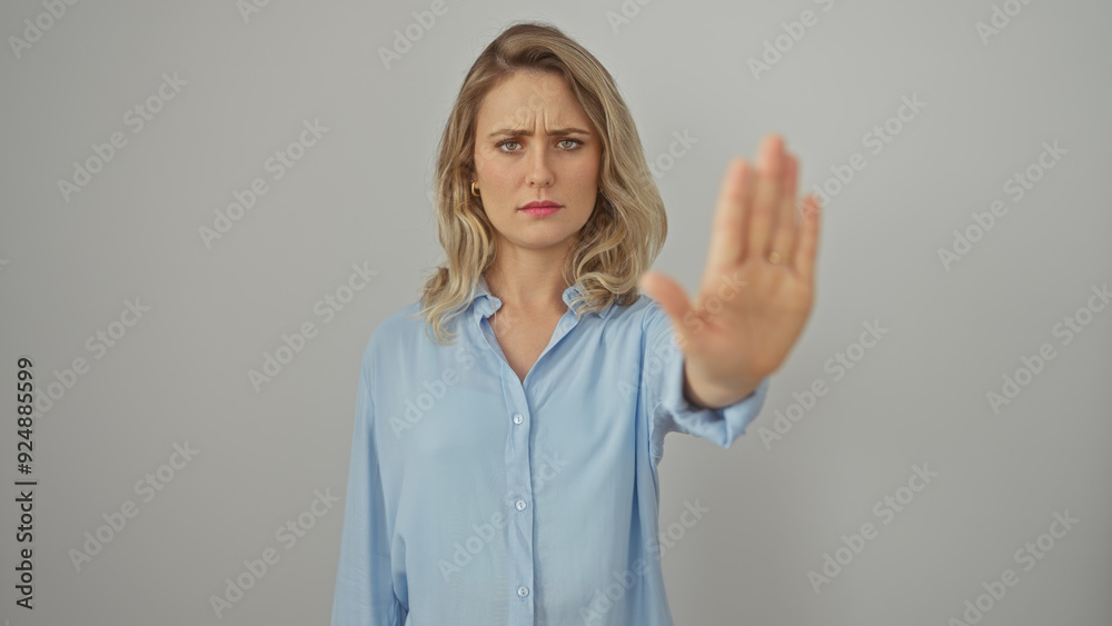 A skeptic young woman in a blue shirt gesturing stop against a white background A skeptic young woman in a blue shirt gesturing stop against a white background