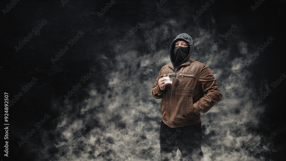 Drug dealer, dangerous hooded criminal man in black mask and brown leather jacket holding transparent plastic bag with drugs and dollar bills, on a dark background with smoke Drug dealer, dangerous hooded criminal man in black mask and brown leather jacket holding transparent plastic bag with drugs and dollar bills, on a dark background with smoke