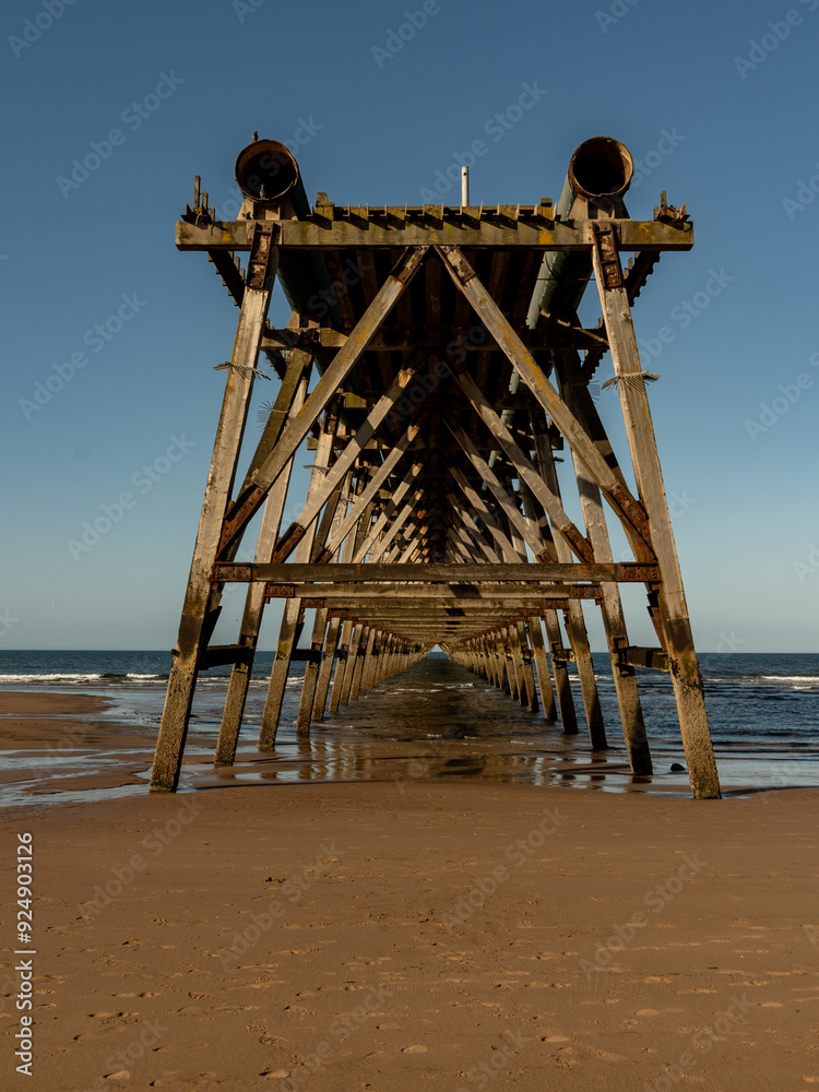 Old wooden pier structure disappearing into the sea at low tide
