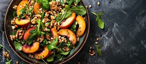 Fresh greens topped with peaches roasted walnuts and pine nuts in a colorful dish with copy space image photo