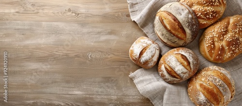 Various freshly baked breads displayed on a beige kitchen towel against a wooden background captured from above with room for copy space image