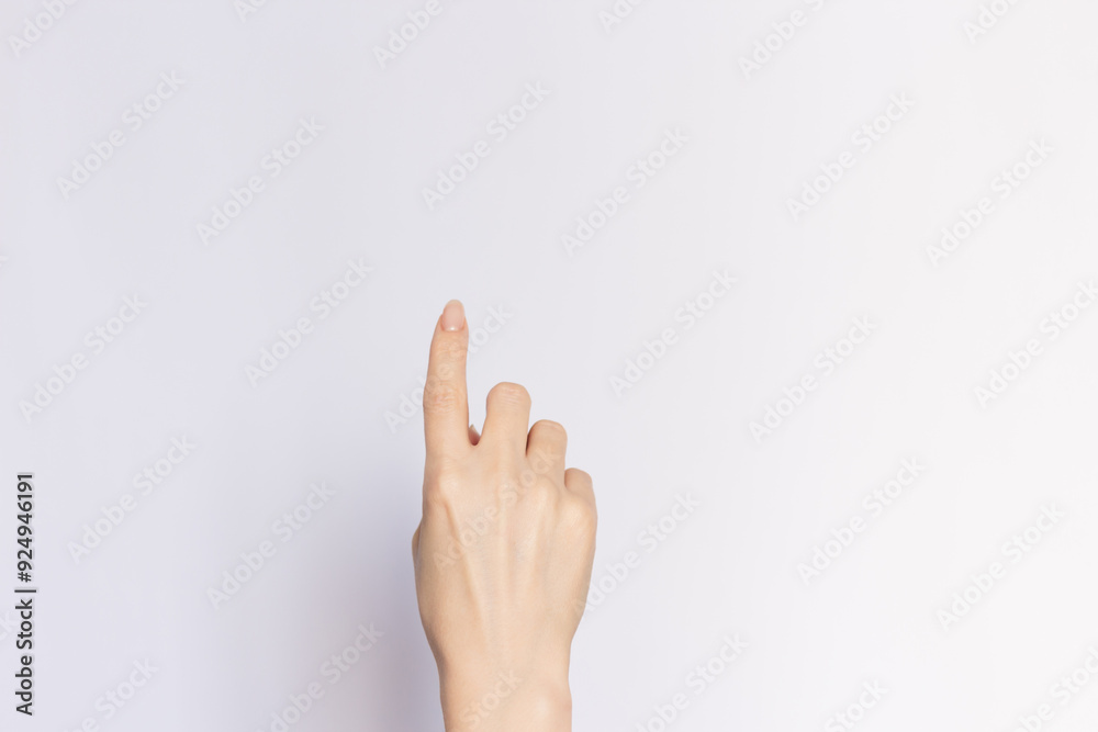 Female hand pointing upwards with index finger, close-up on an empty white background. Female hand pointing upwards with index finger, close-up on an empty white background.