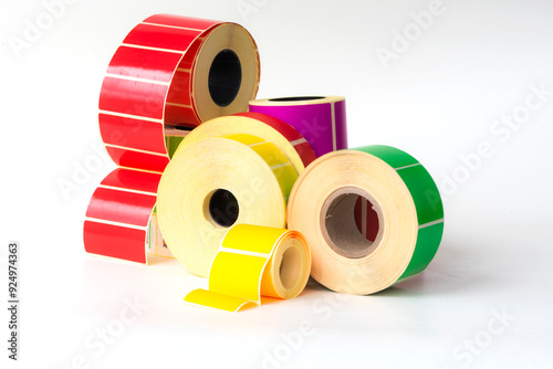 Reels of self-adhesive clean colored labels on a white background on different cores for printing barcodes, information, QIAR codes, logistics information.