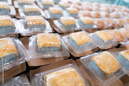 Homemade almond cakes are placed on blue paper in a clear plastic box, arranged in a row