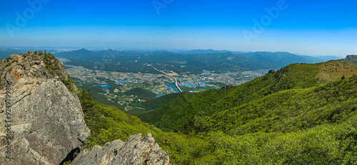 Spring and panoramic view of rocks and ridges of Shinbulsan Mountain against rice paddy and houses of a village at Yeongnam Alps near Ulju-gun, Ulsan, South Korea photo