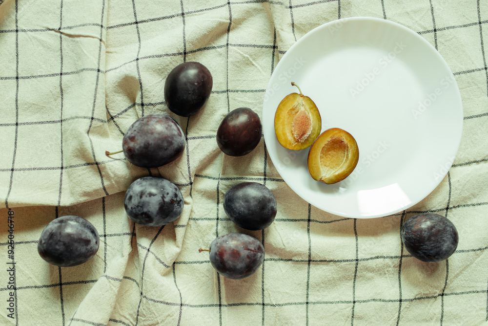 Plums on a white table on a check kitchen towel, vintage style Plums on a white table on a check kitchen towel, vintage style